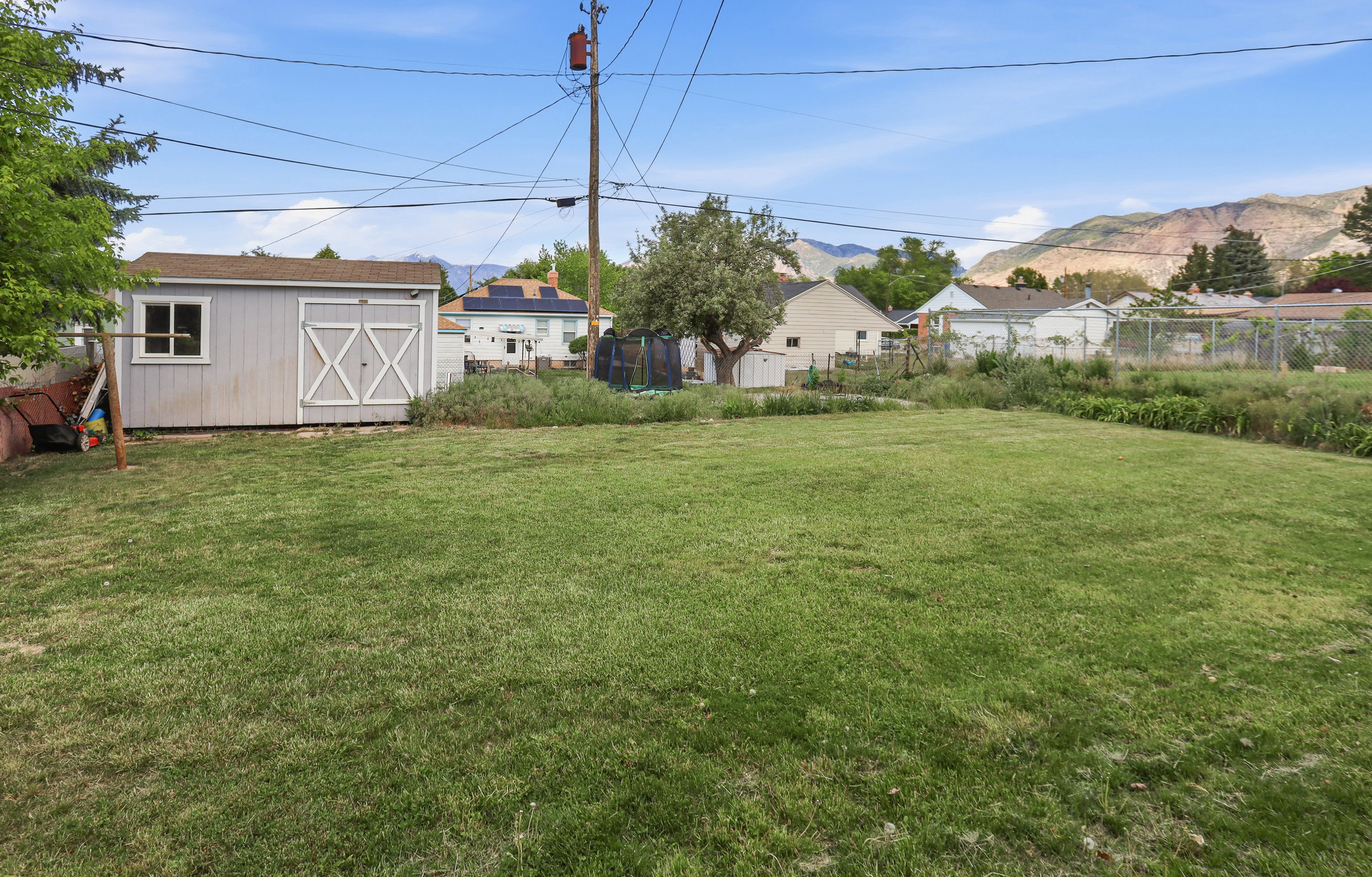 Expansive grassy yard area featuring a detached storage shed with a window and double barn doors