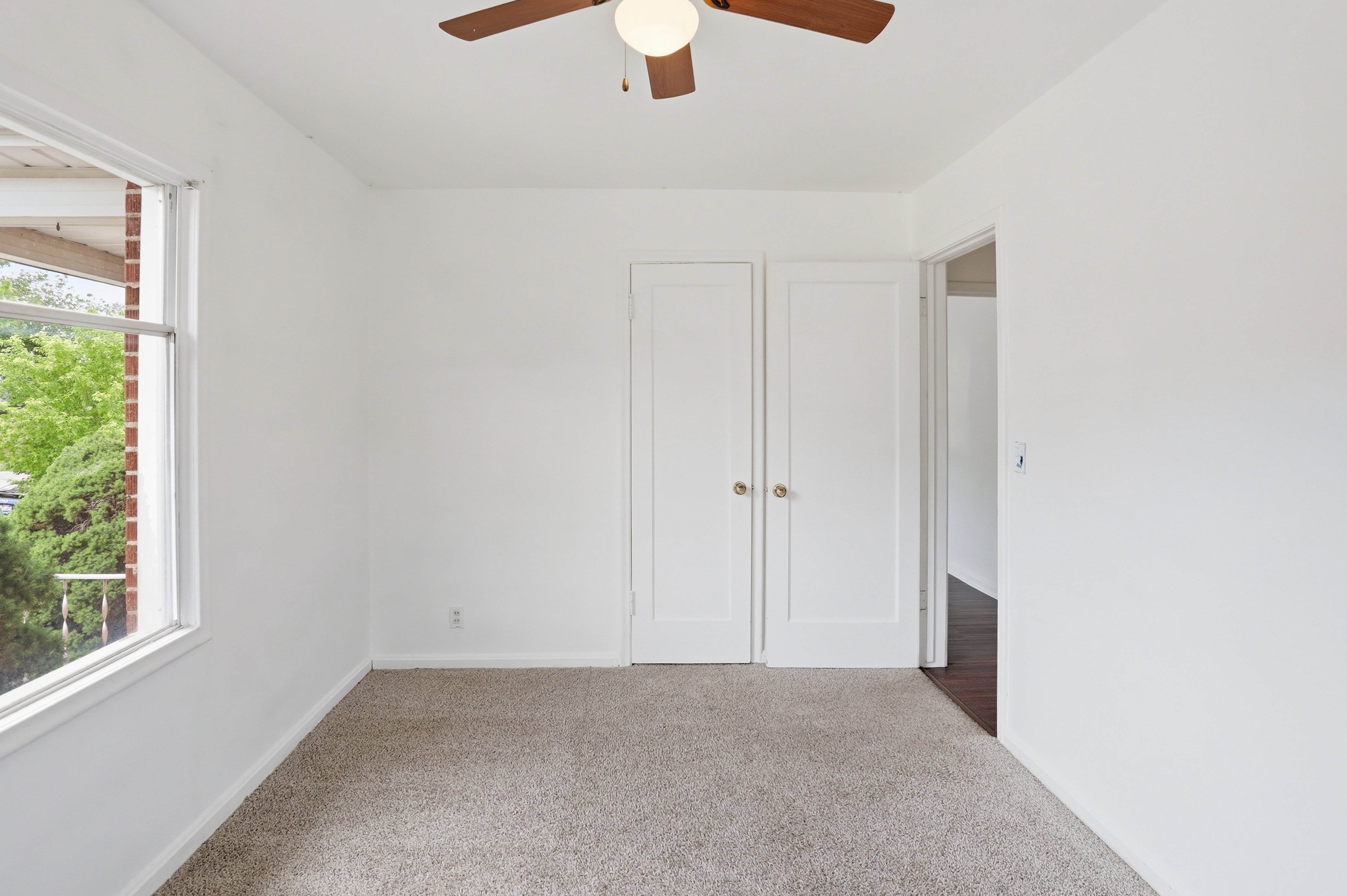 Neutral-toned carpeting paired with white walls, featuring a ceiling fan with integrated lighting
