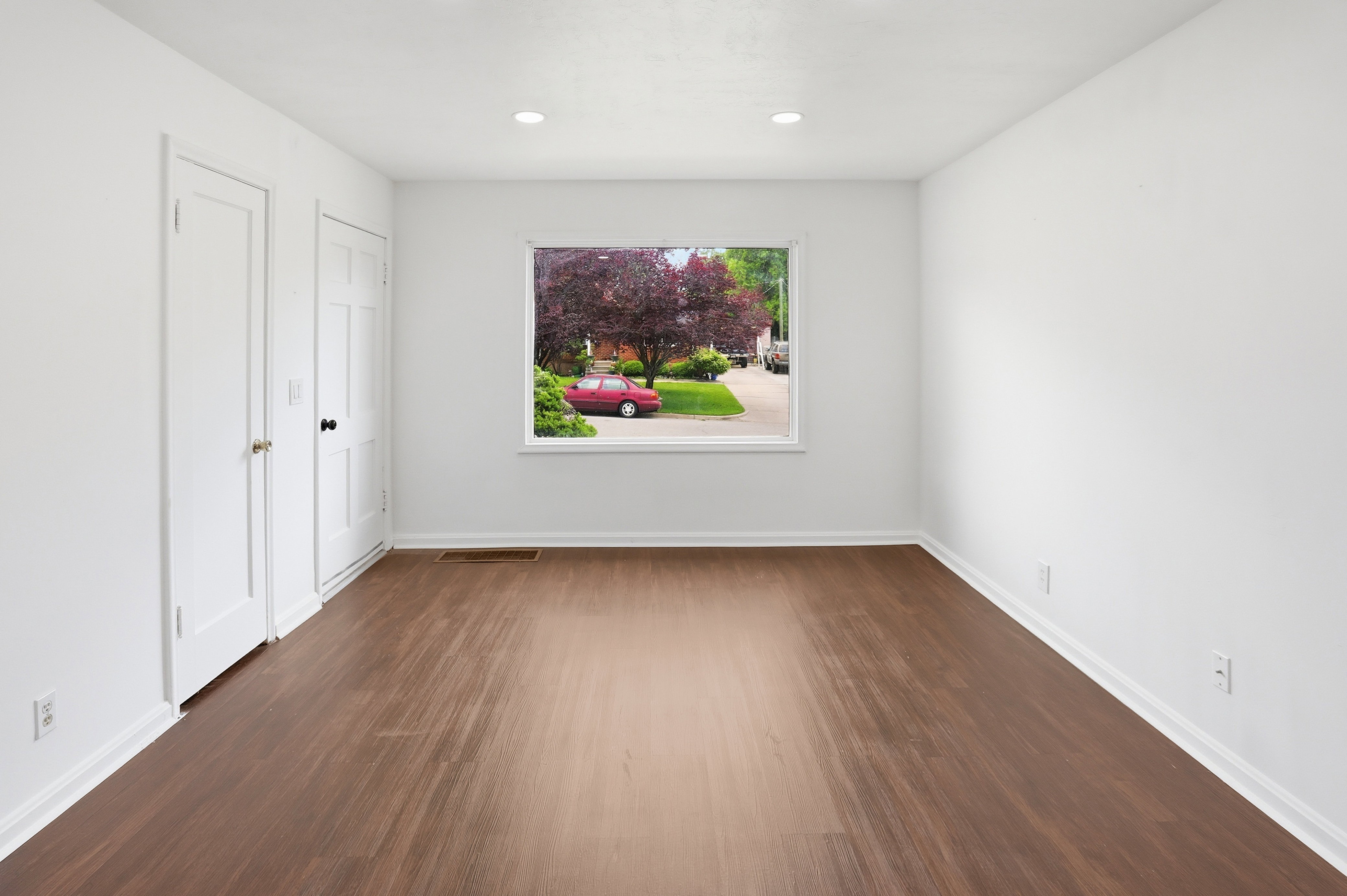 Spacious room featuring wood-finish flooring and bright white walls