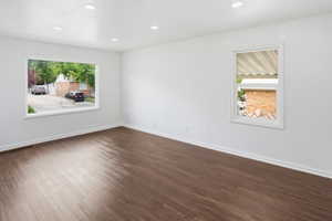 Spacious interior room featuring wood-finish flooring, crisp white walls, and recessed lighting