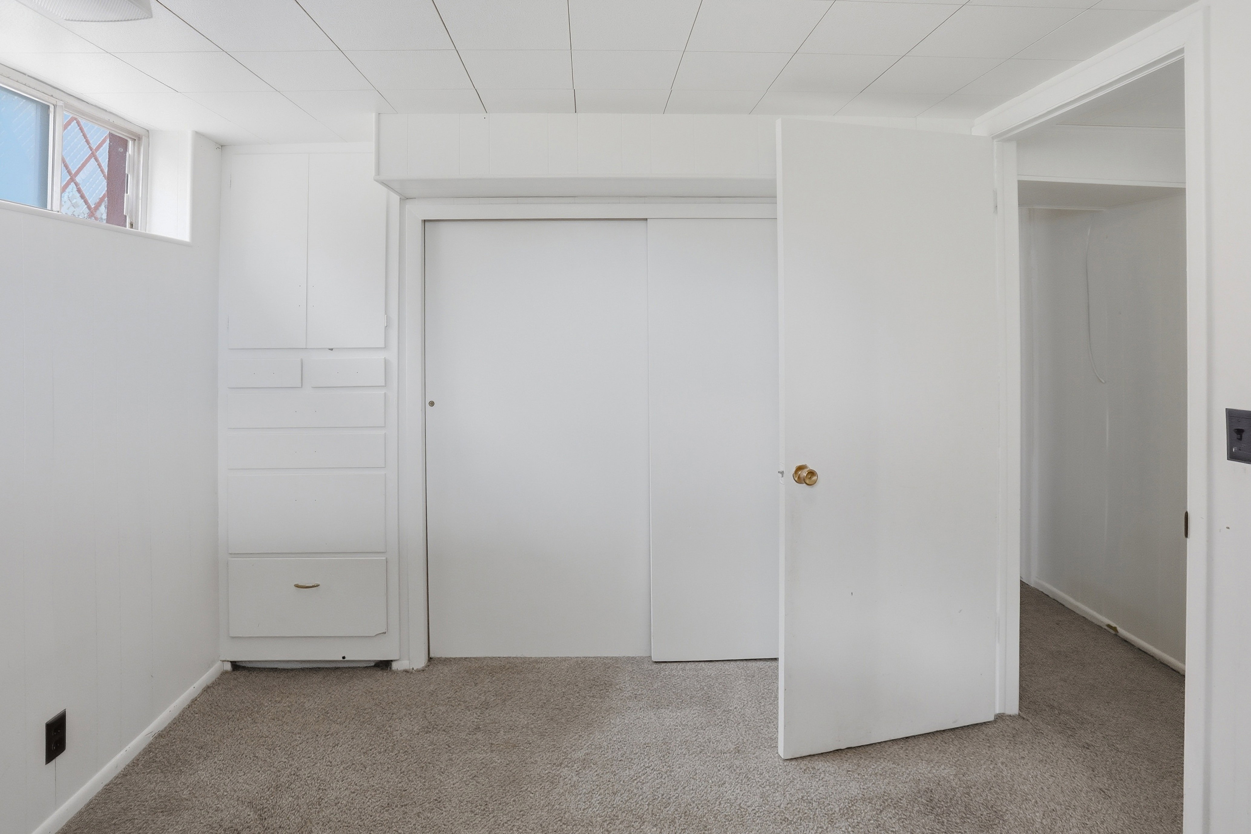 Carpeted flooring throughout, white painted walls, and a white drop ceiling