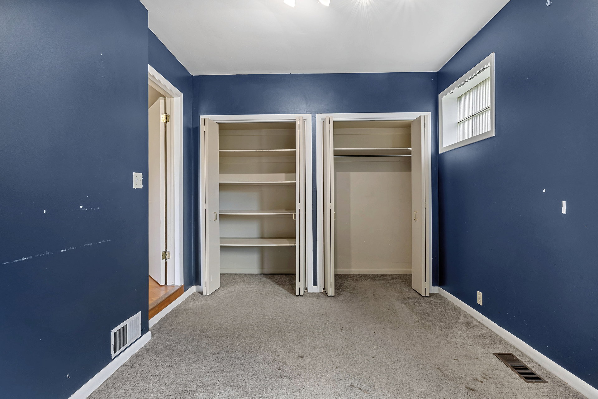 Room featuring two bi-fold door closets, one with built-in shelving