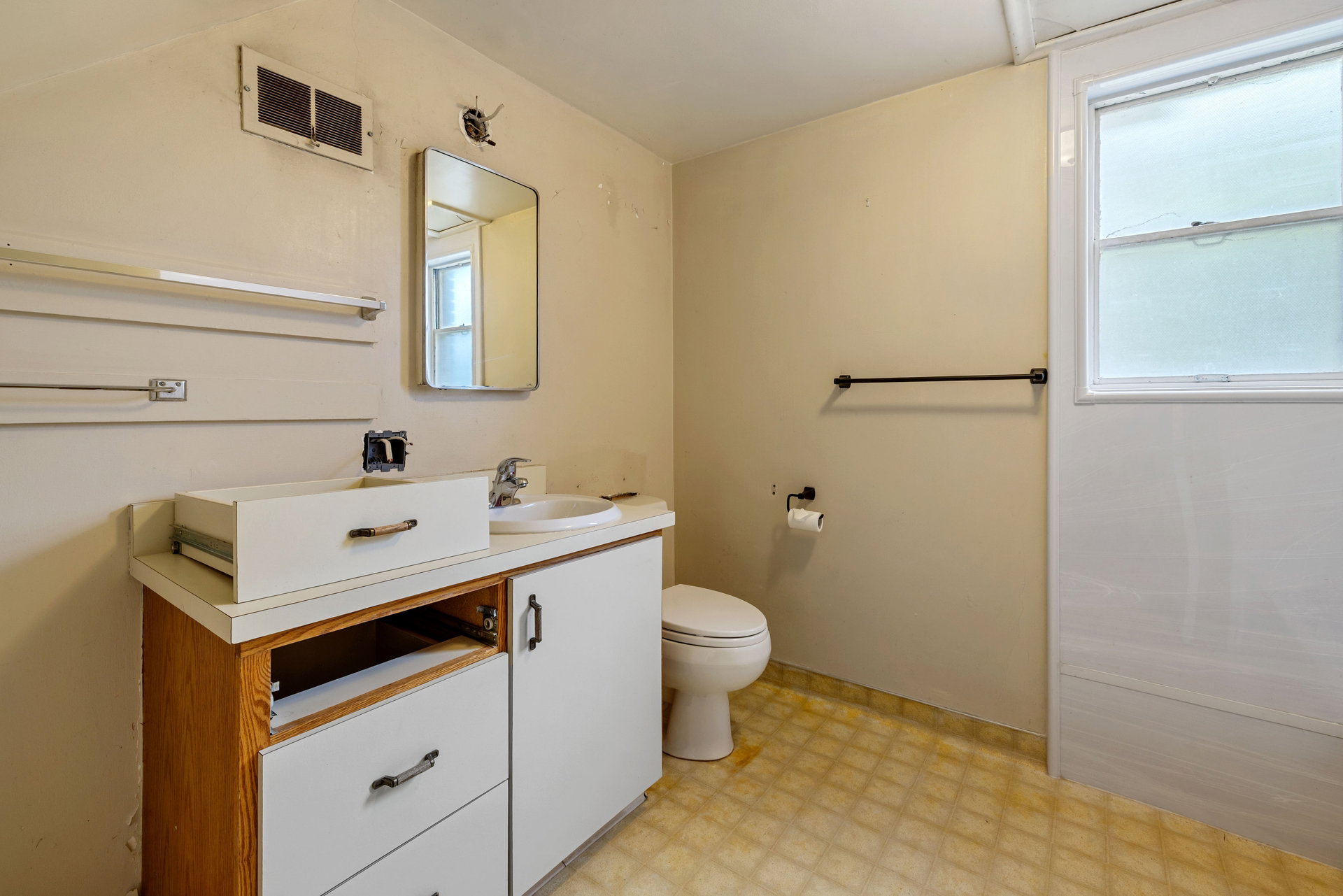 Bathroom featuring a built-in vanity with a white countertop and wood-finish base, an integrated sink, a wall-mounted mirror, and a window with white trim