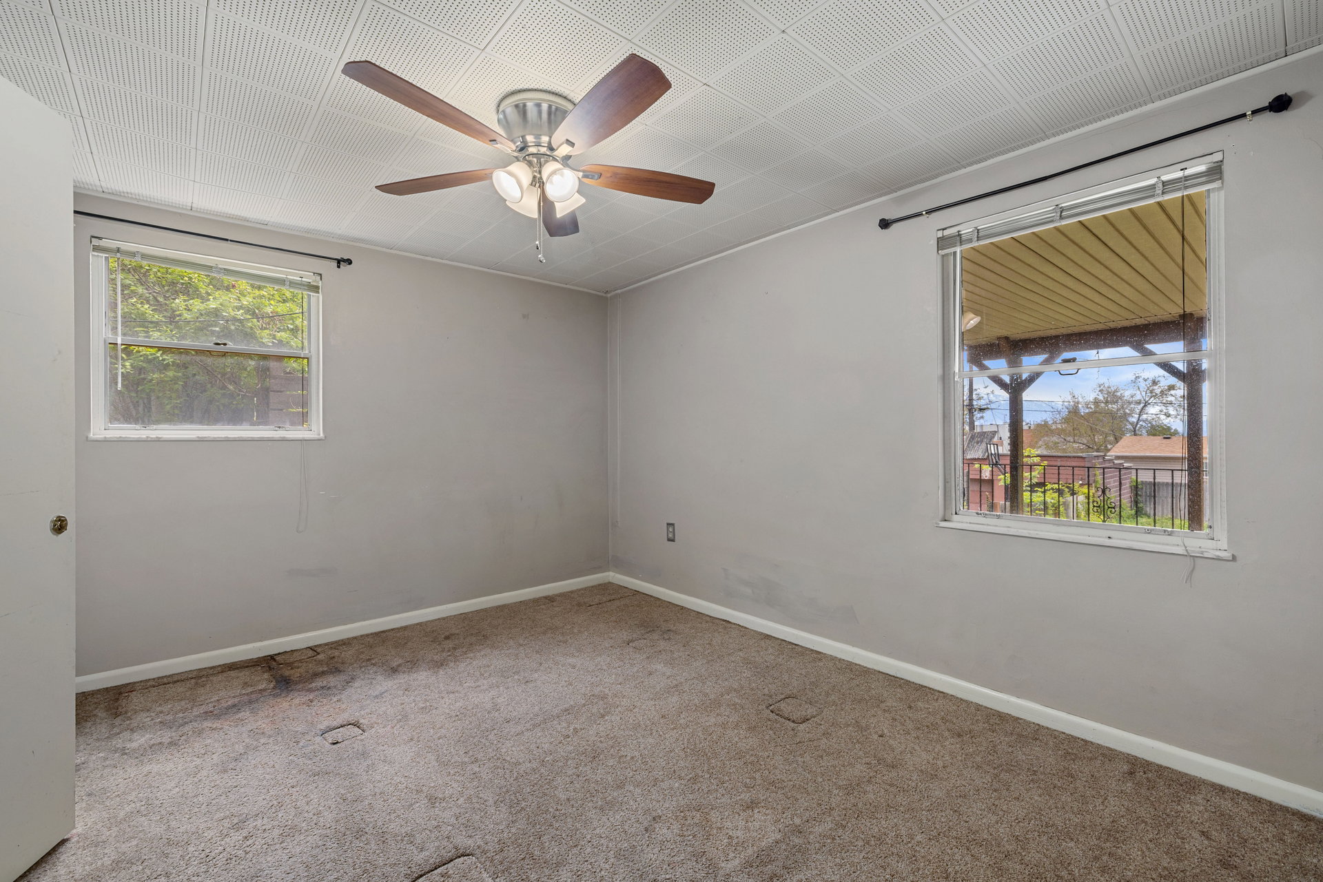 Bedroom featuring a ceiling fan with integrated lighting, two windows, and light gray wall paint