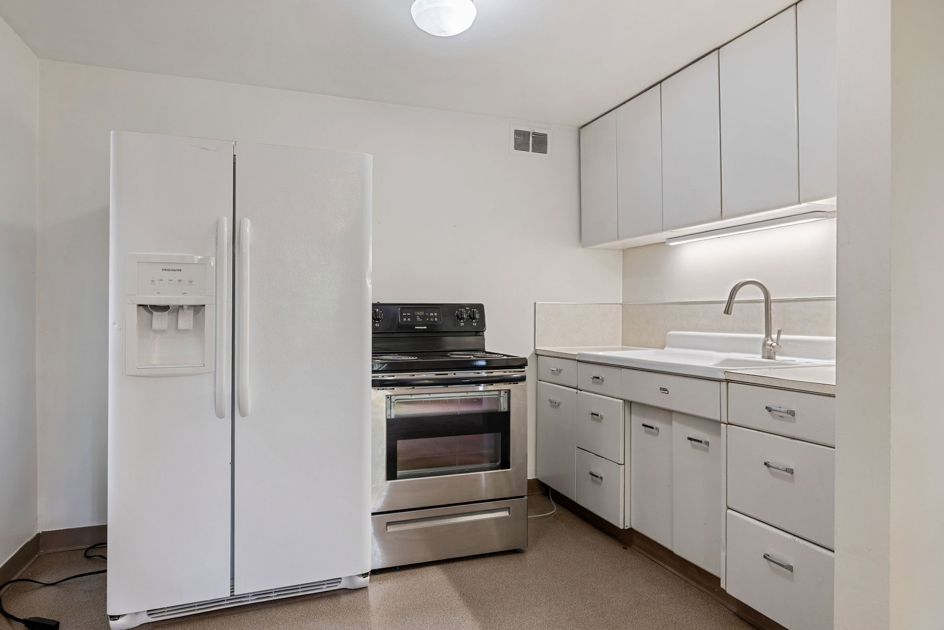 Kitchen featuring white cabinetry, a stainless steel range, and a side-by-side refrigerator with dispenser
