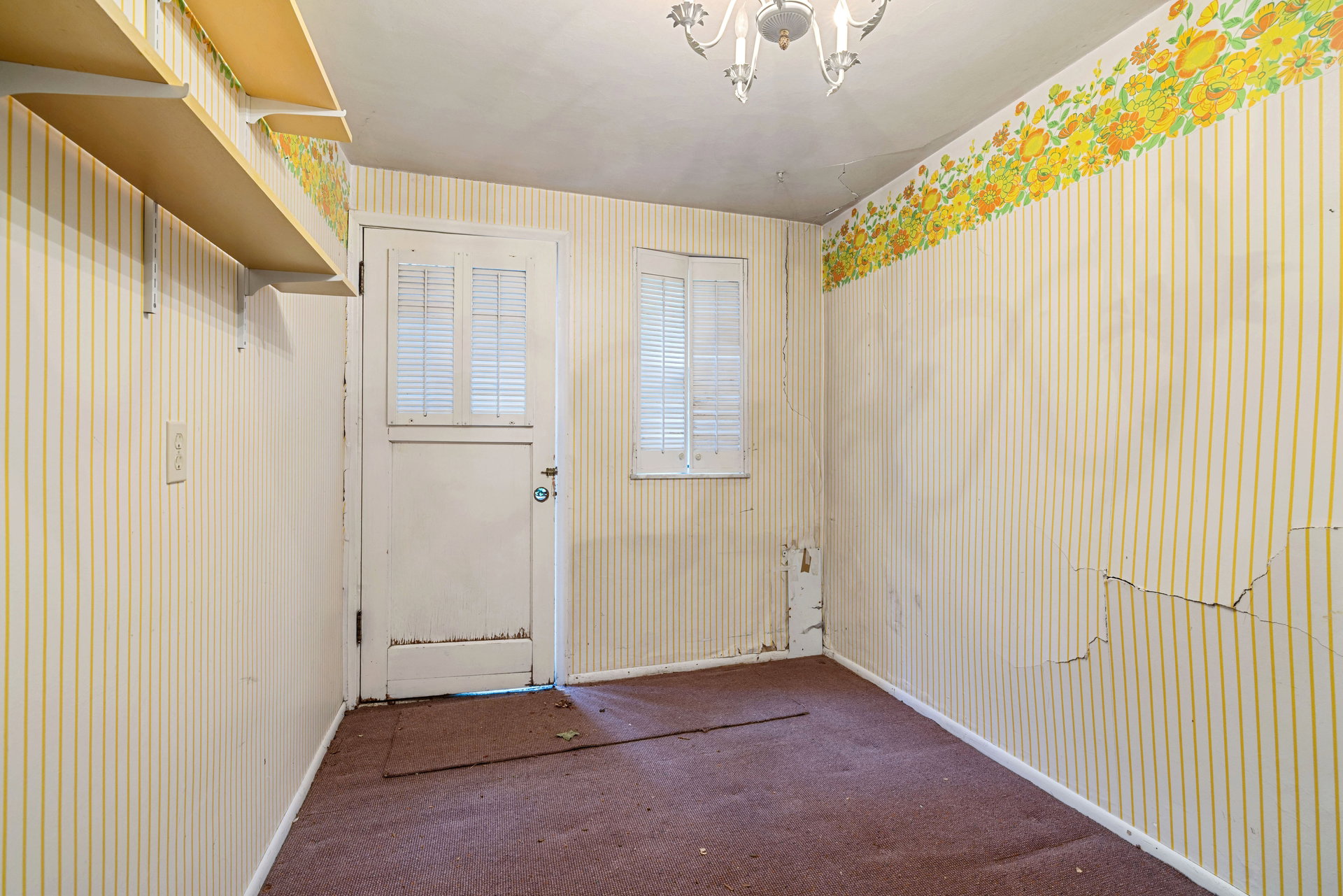 Room featuring patterned wallpaper, carpet flooring, and a chandelier
