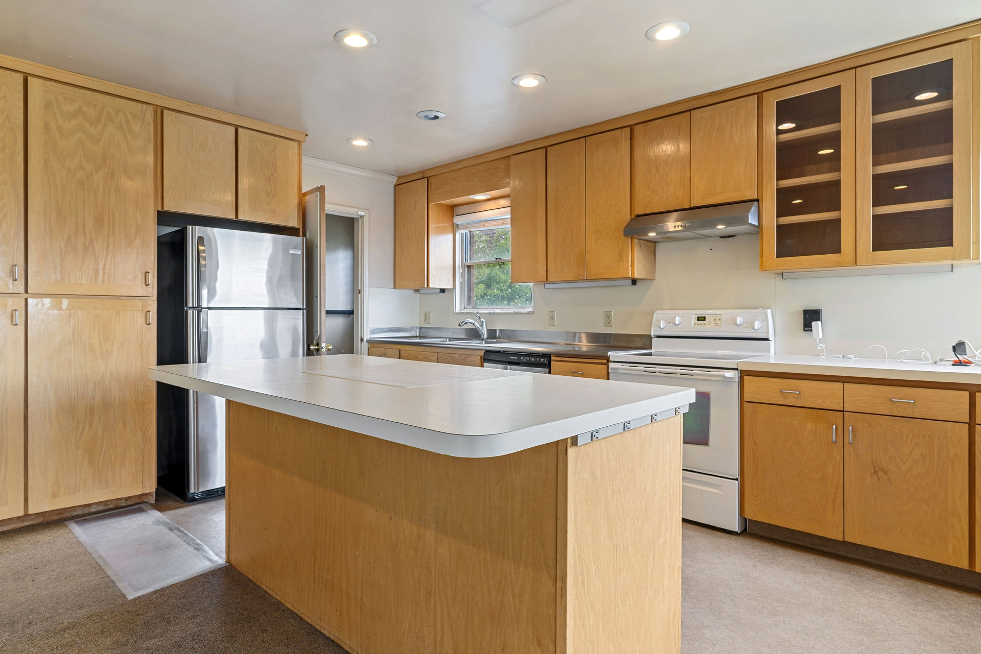 Kitchen featuring an expansive island, abundant wood-finish cabinetry, a stainless steel refrigerator, white electric range, and recessed lighting
