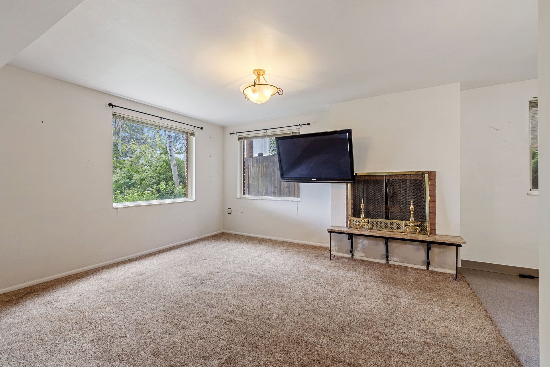 Carpeted room featuring a brick fireplace with a stone mantel
