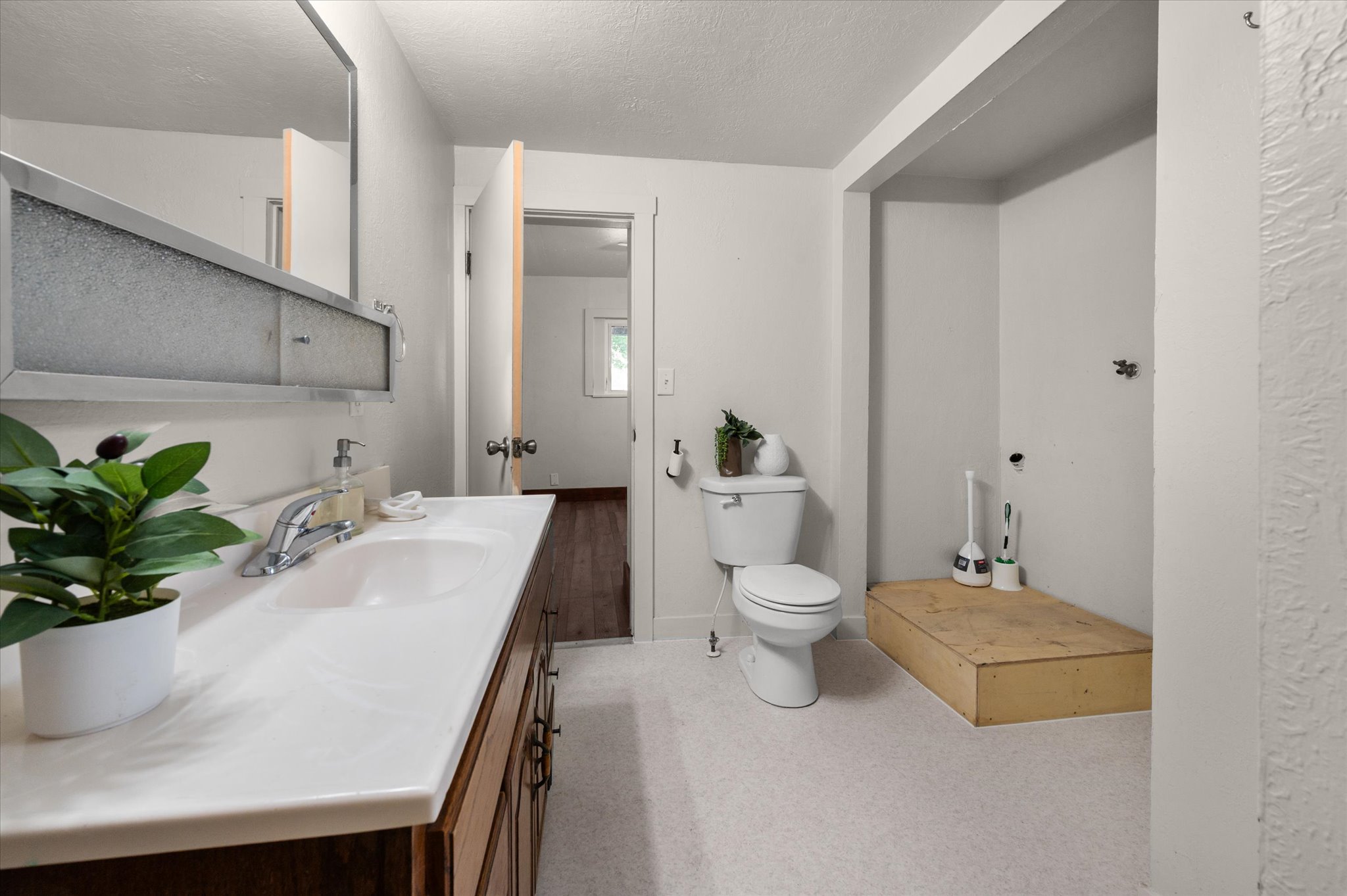 Bathroom with wood-finish vanity, white countertop, integrated sink, and an overhead medicine cabinet with frosted glass panels