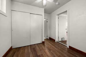 Interior room featuring wood-finish flooring, white walls, and a white ceiling fan