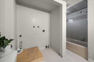 Utility area with washer hookups and a full bathroom featuring a tub with an integrated shower