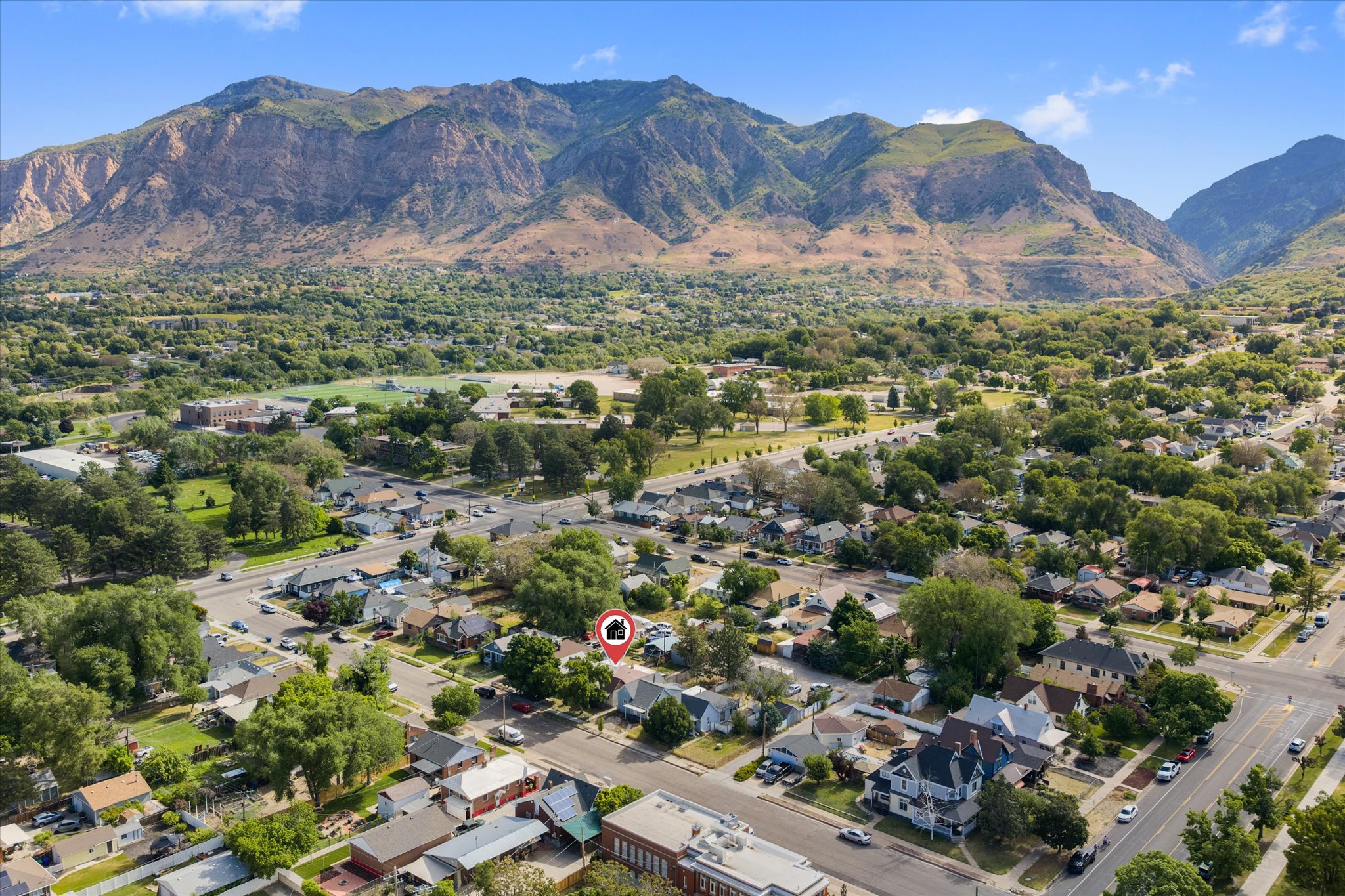 Property situated in a residential neighborhood with mature trees, featuring a prominent mountain backdrop