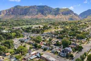 Property situated in a residential neighborhood with mature trees, featuring a prominent mountain backdrop