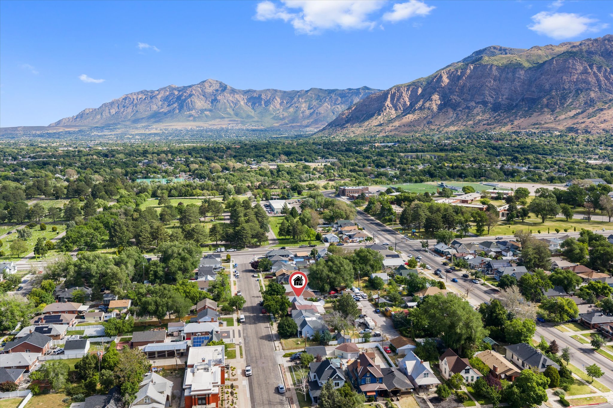 Aerial perspective showcasing the property's setting amidst residential streets, mature trees, and a mountain backdrop