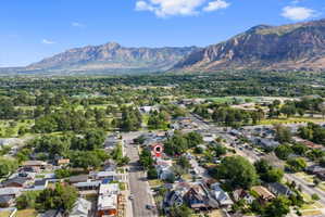 Aerial perspective showcasing the property's setting amidst residential streets, mature trees, and a mountain backdrop