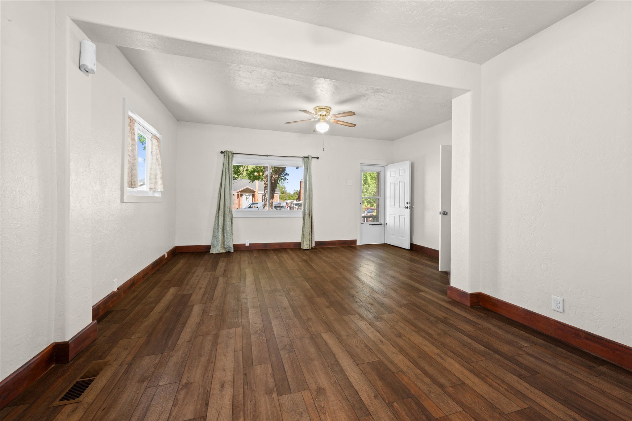 Expansive interior space featuring wood-finish flooring, white walls, and a ceiling fan with integrated lighting