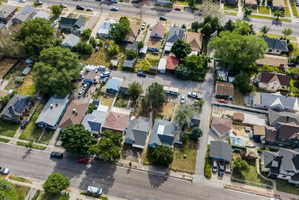 Aerial view of a residential neighborhood with diverse roofing styles, mature trees, and paved streets