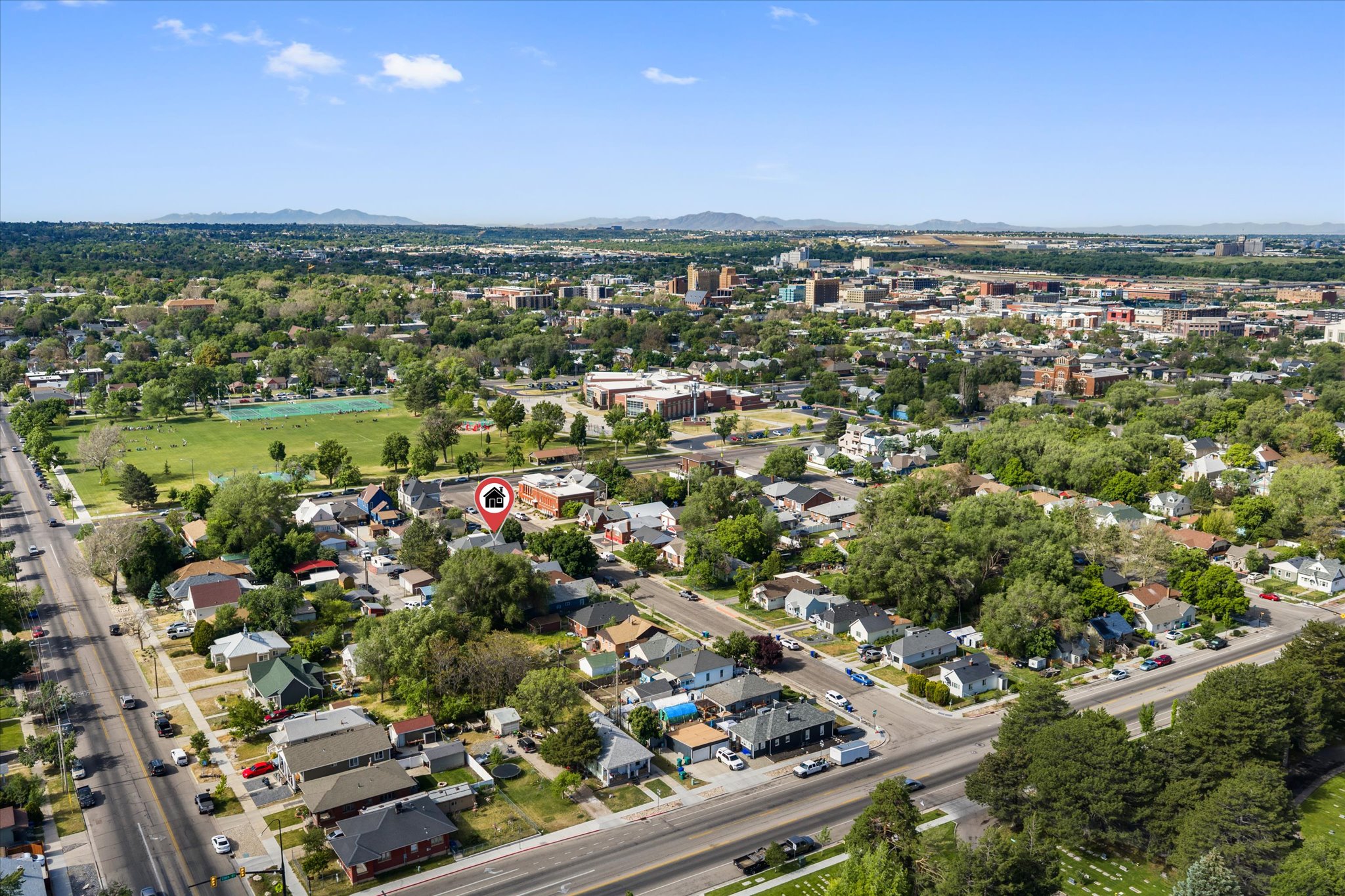 Aerial perspective showcasing a residential neighborhood with mature trees and proximity to urban amenities and distant mountains