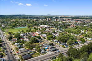 Aerial perspective showcasing a residential neighborhood with mature trees and proximity to urban amenities and distant mountains