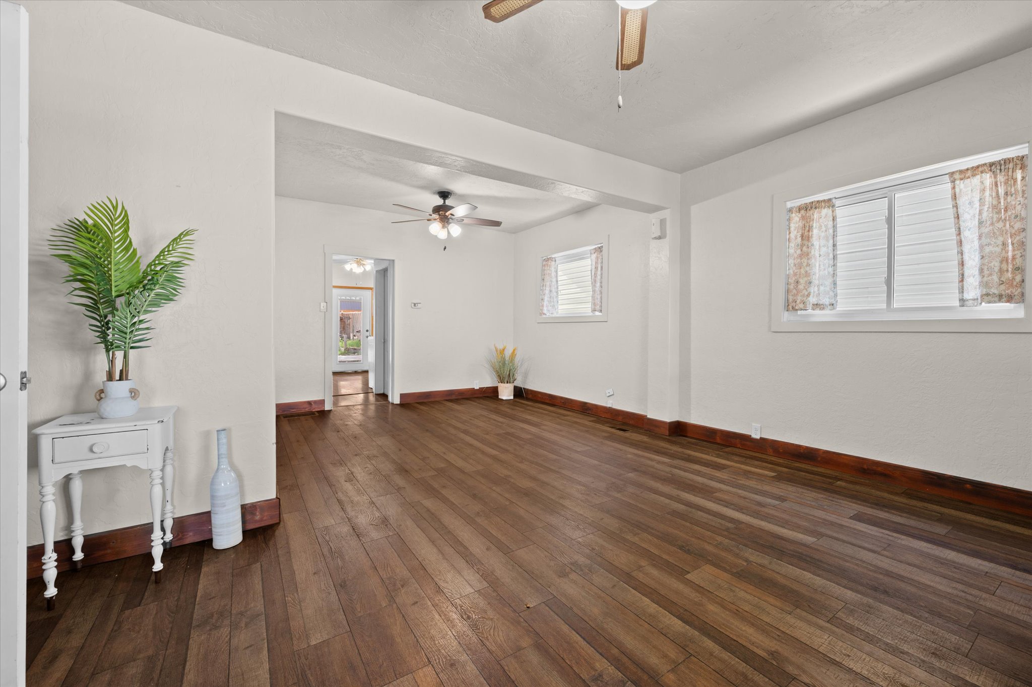 Spacious room featuring wood-finish flooring, white walls, and multiple windows