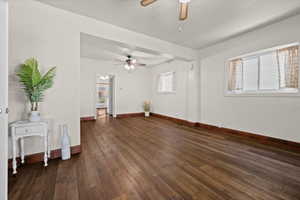 Spacious room featuring wood-finish flooring, white walls, and multiple windows