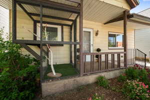Covered front entry porch with horizontal siding, an exterior wall sconce, and a wood railing
