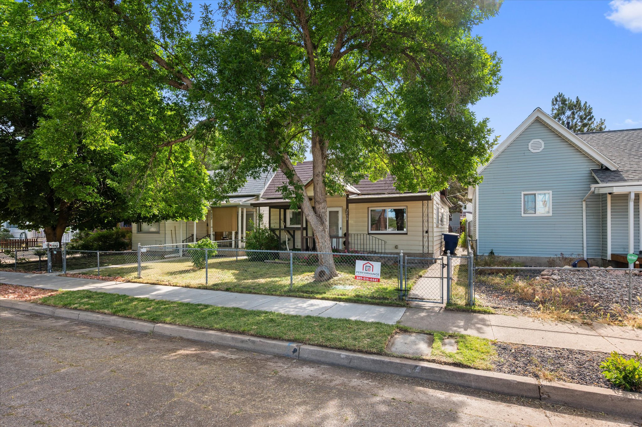 Single-story residence featuring a covered front porch and a chain-link fence enclosing the front yard