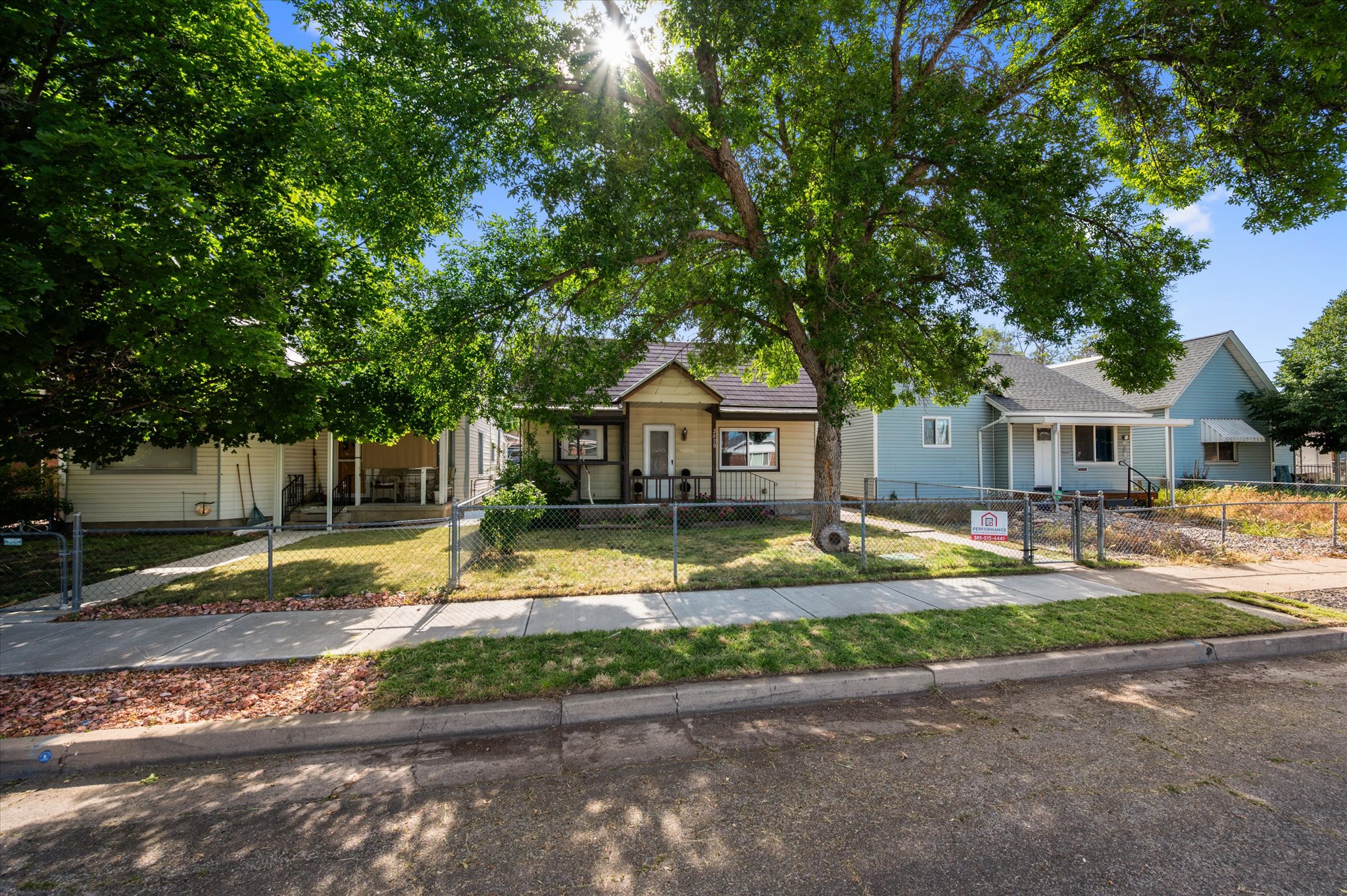 Charming bungalow-style residence featuring a covered front porch, white railing, and chain-link fencing