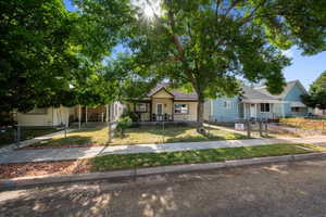 Charming bungalow-style residence featuring a covered front porch, white railing, and chain-link fencing