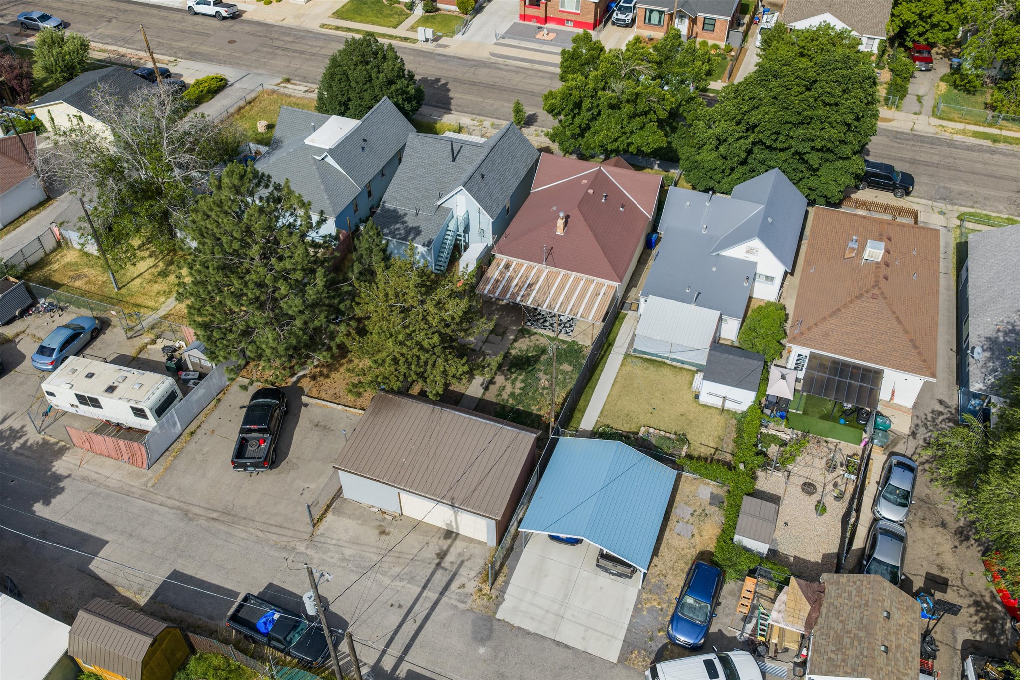 Residential property featuring multiple structures, a paved drive, and a detached garage with a metal roof