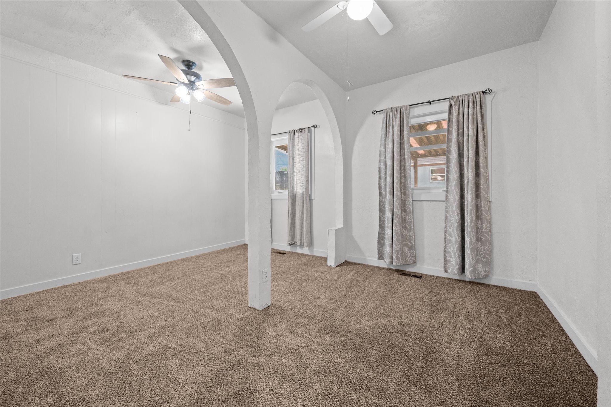 Arched doorways defining distinct spaces, complemented by plush brown carpeting and white wall finishes