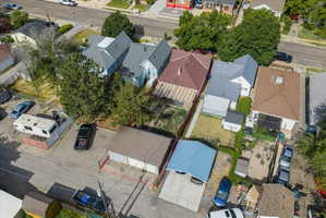 Aerial perspective showcasing a light blue residence with a dark gray roof, accompanied by a detached brown-roofed structure and a separate brown two-car garage