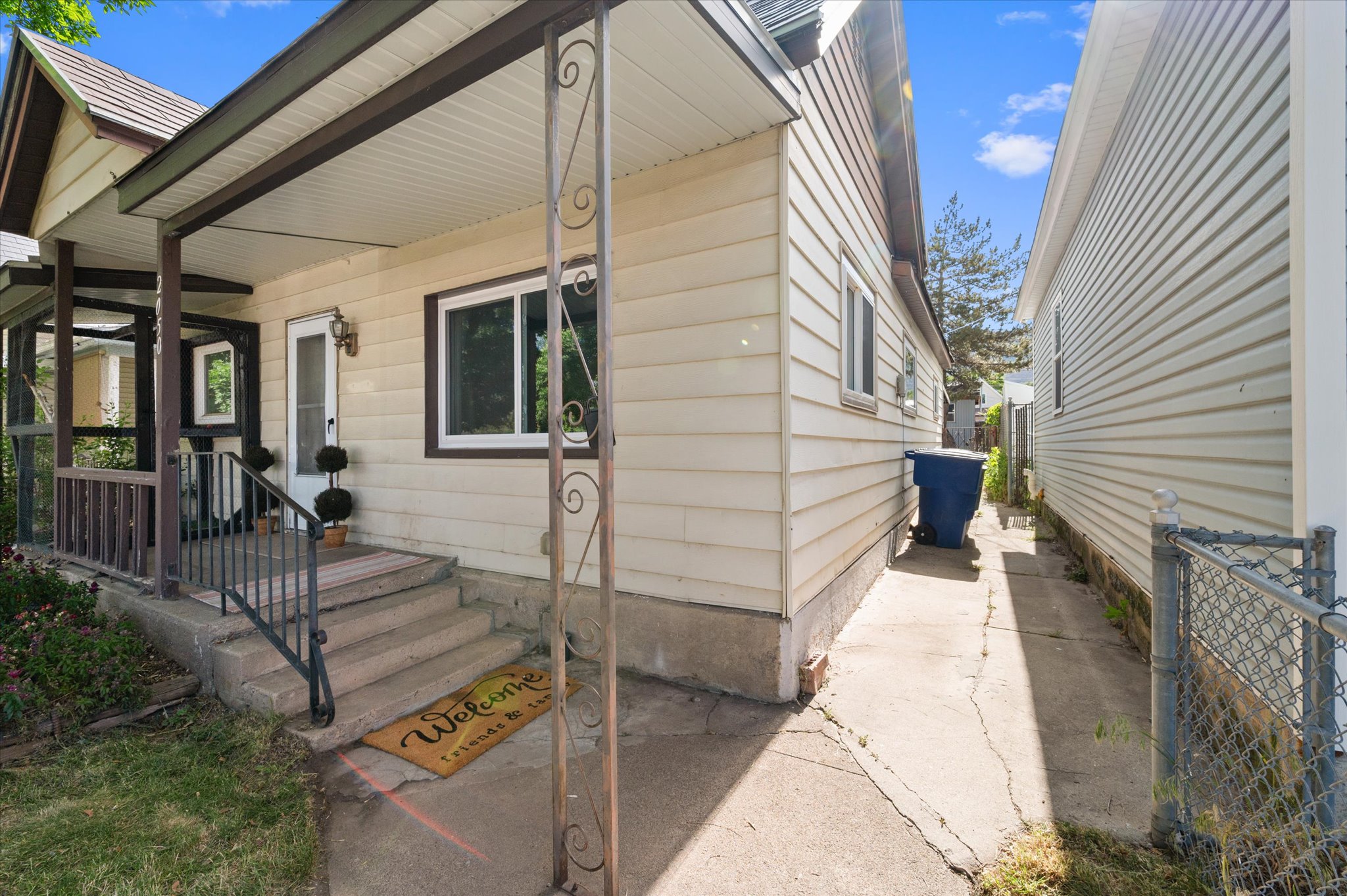 Property exterior featuring light-colored siding, a covered front porch with dark trim, a white entry door, and a screened-in porch area