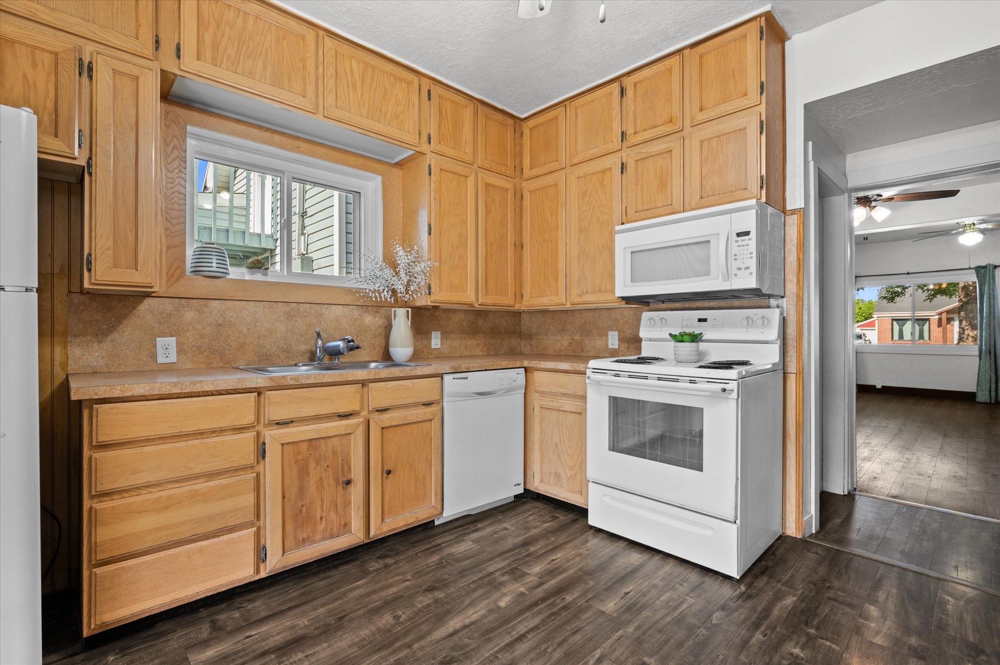 Kitchen featuring wood cabinetry, laminate countertops, a double basin sink, and wood-finish flooring