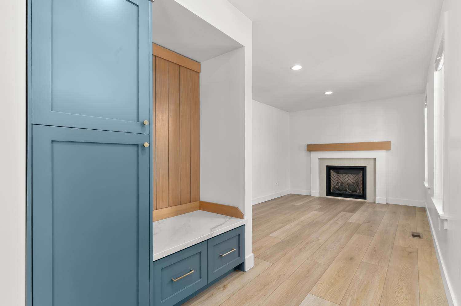 Built-in storage cabinetry with blue finish, complemented by a wood-paneled bench with a stone-finish top and integrated drawers