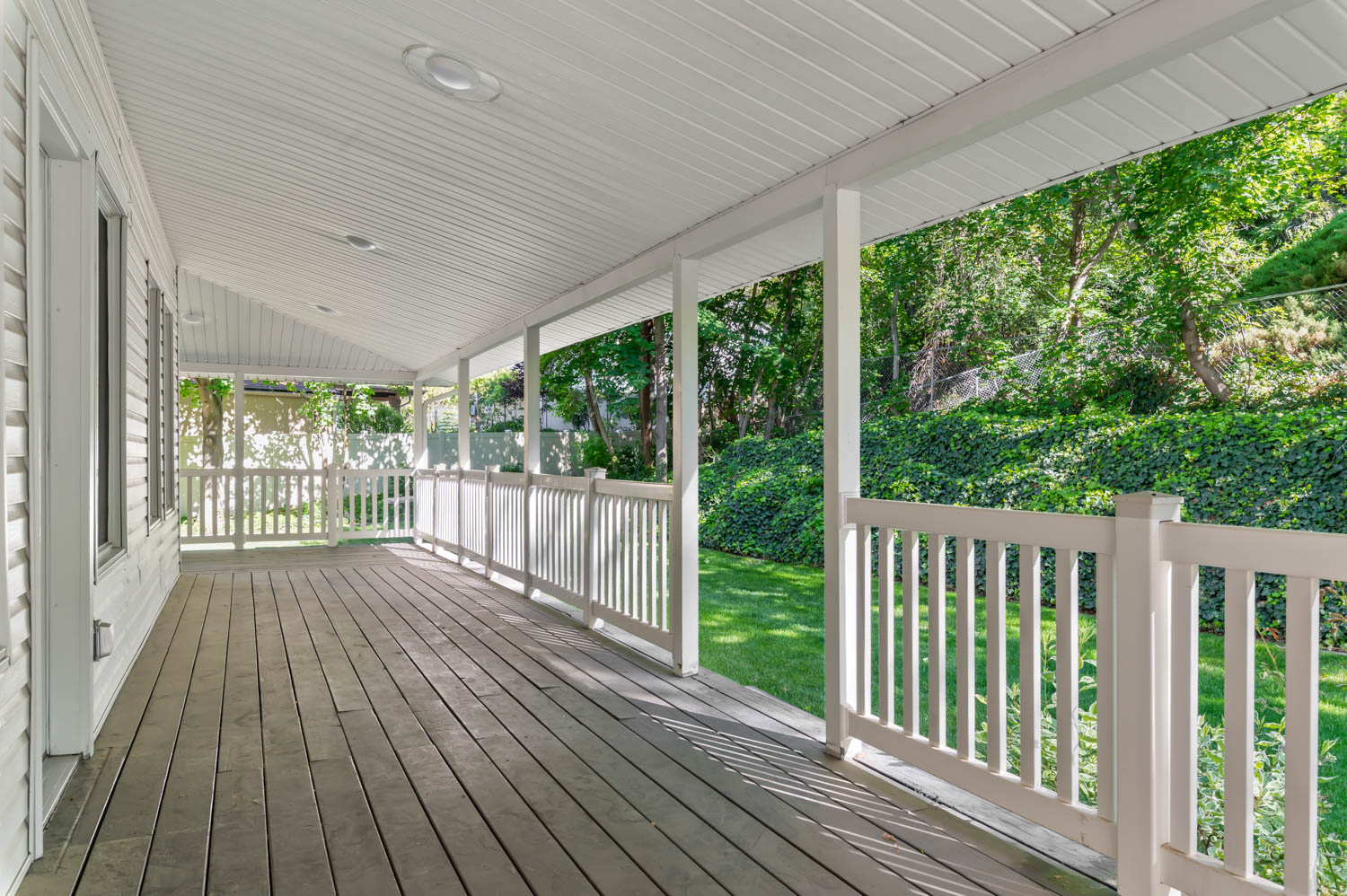 Spacious covered porch featuring wood-finish flooring and white railings