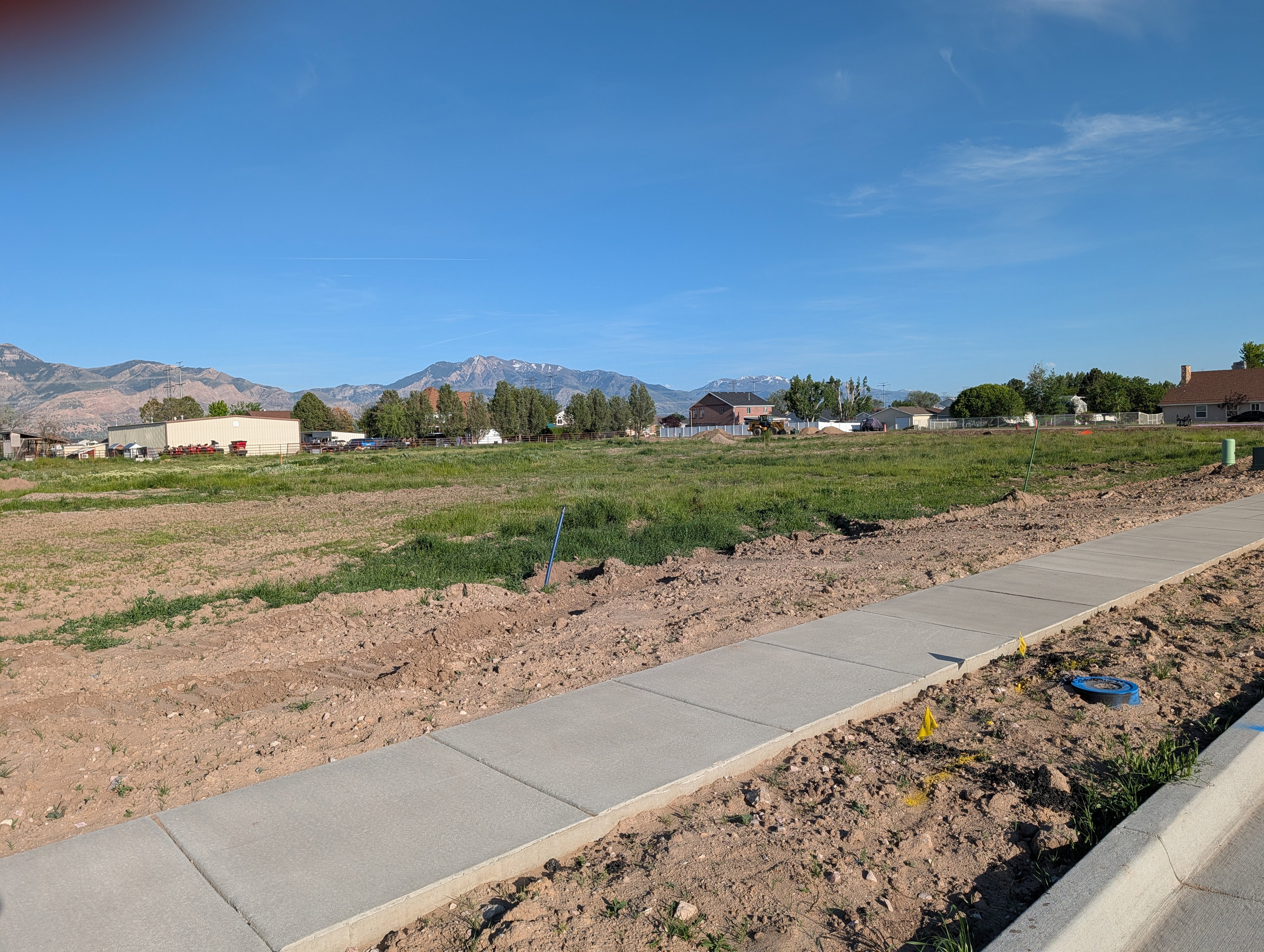 Expansive land parcel featuring new concrete sidewalks and a mountain backdrop