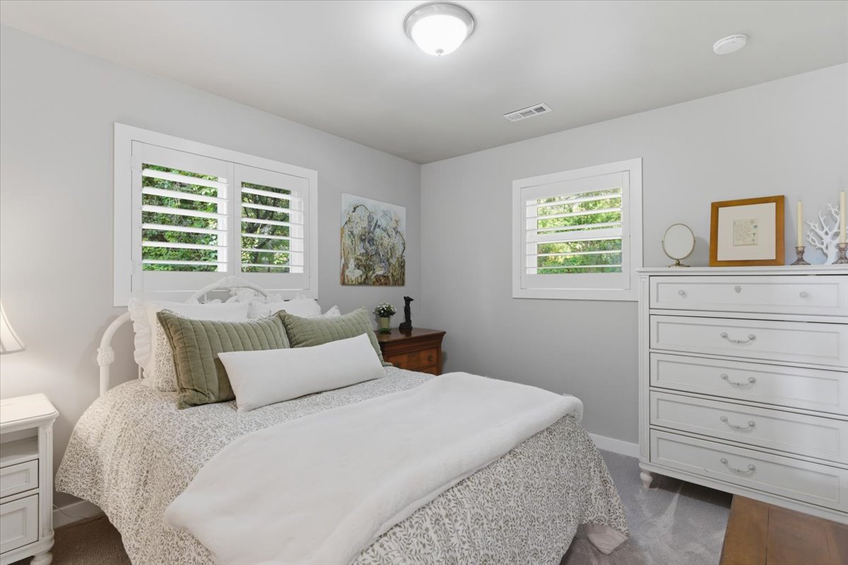 Bedroom featuring two windows with white plantation shutters