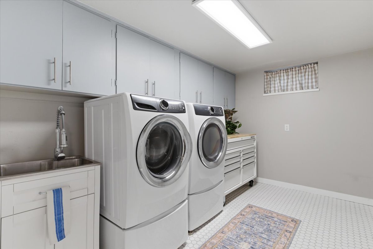 Dedicated utility space featuring extensive overhead cabinetry, a dual-basin stainless steel sink with a gooseneck faucet, and hexagonal floor tiling