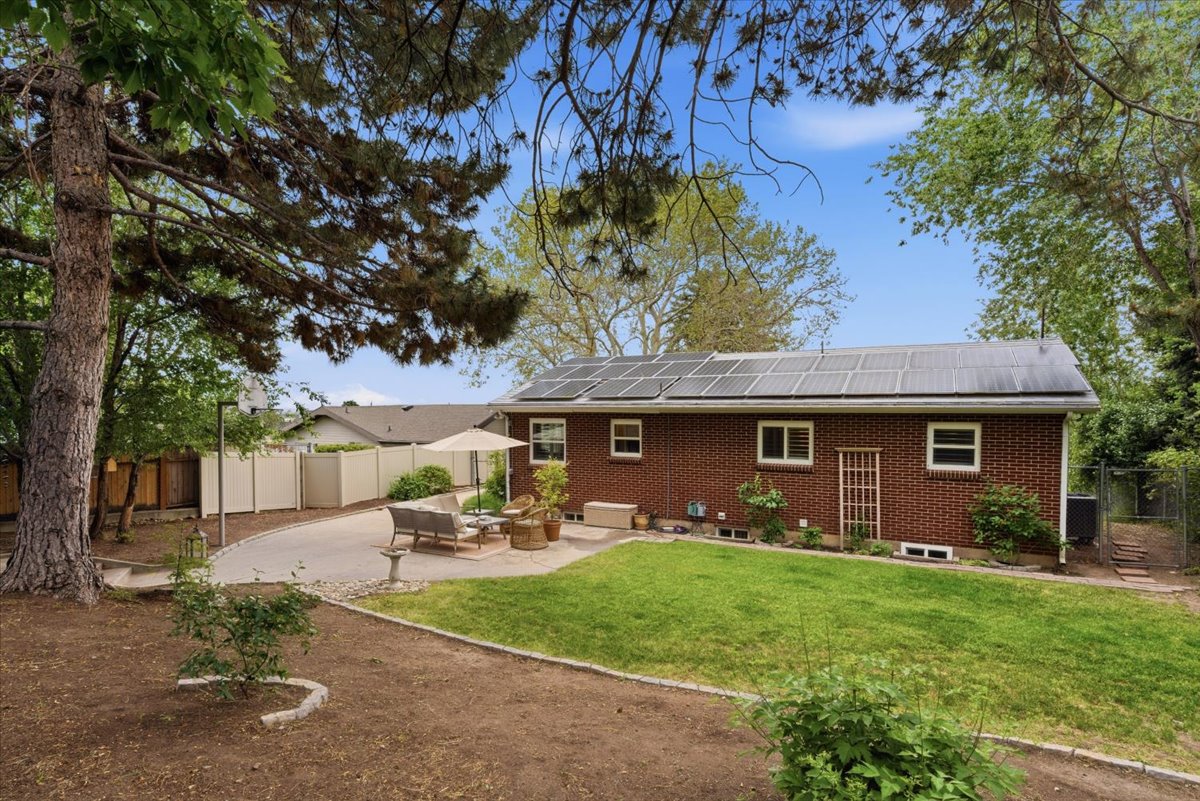 Expansive backyard featuring a brick exterior, solar panel array, and a spacious paved patio