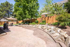 Multi-level stamped concrete patio with stone retaining wall, wooden privacy fencing, and mature trees