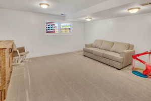 Spacious room featuring neutral carpeting, white walls, and a window with white plantation shutters
