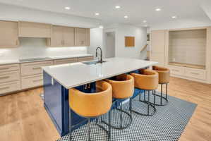 Kitchen island with a white countertop and integrated sink, complemented by light wood-finish flooring