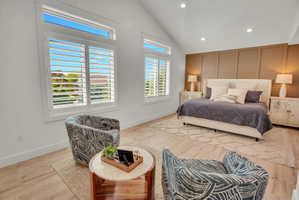Spacious room featuring vaulted ceilings, light wood-finish flooring, and recessed lighting