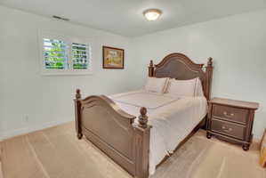 Room featuring neutral-toned carpeting, white walls, and a window with white plantation shutters