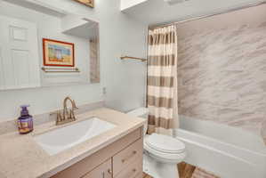 Bathroom vanity with a light-toned countertop and an integrated sink, featuring a polished brass faucet
