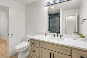 Bathroom featuring a light-toned vanity with black hardware, white countertop, and integrated sink