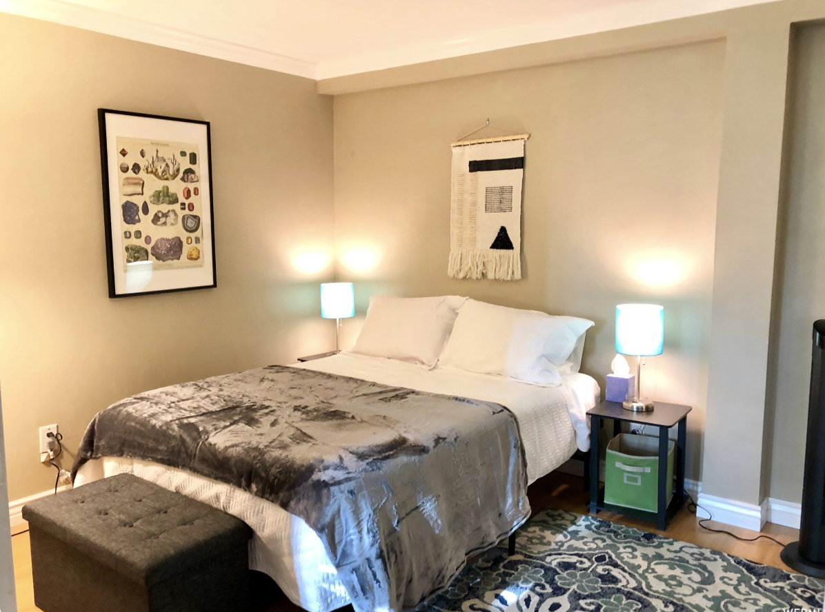 Bedroom featuring light beige walls, crown molding, and wood-finish flooring