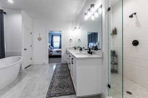 Contemporary bathroom featuring a freestanding tub, dual vanity with undermount sinks and black fixtures, and a glass-enclosed shower with subway tile surround