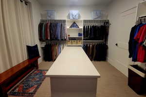 Custom closet system featuring a central island with a solid surface countertop, multiple hanging rods, integrated shelving, and neutral tone carpeting